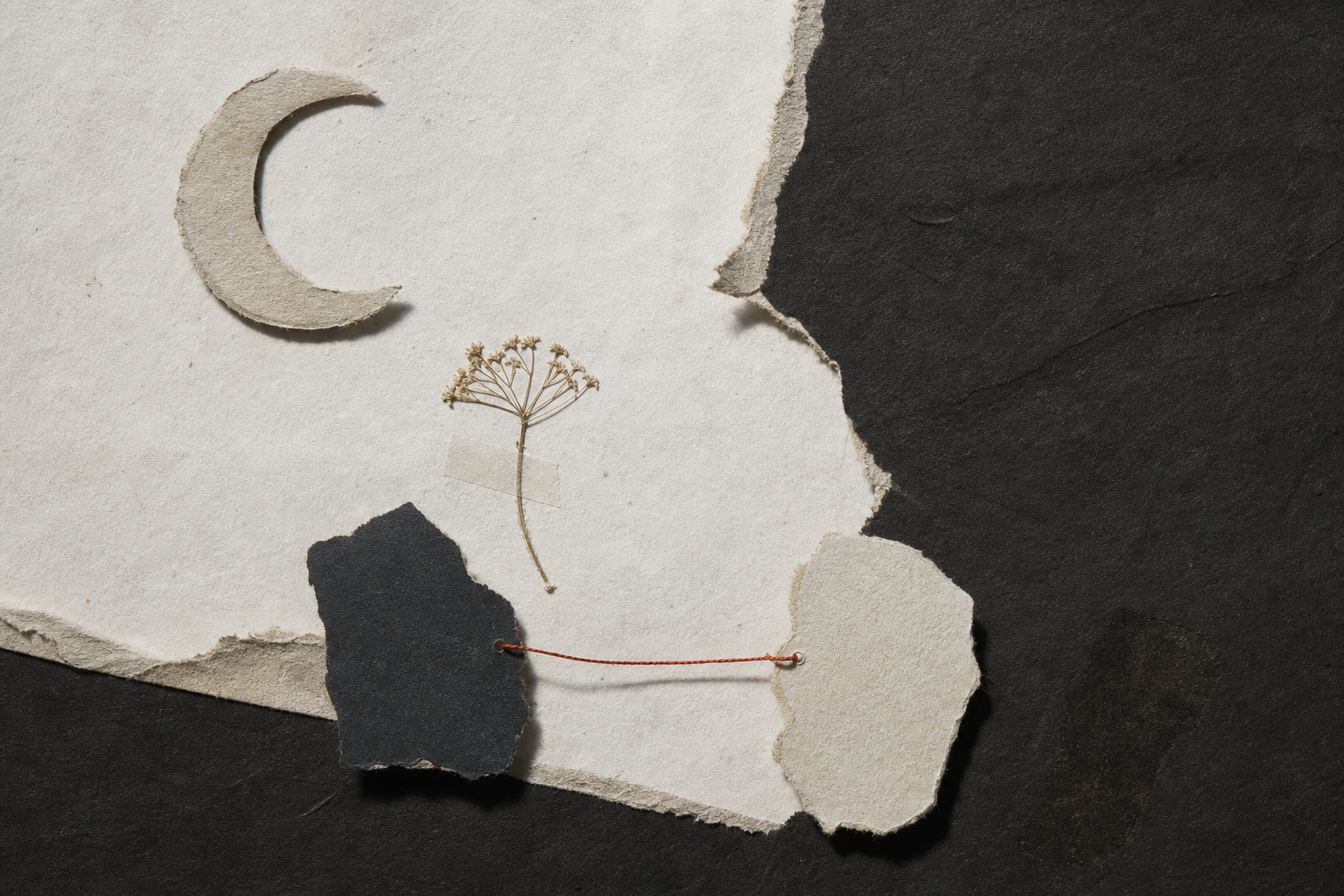 Handmade paper collage with a crescent moon, pressed flower, torn shapes, and a fine red thread