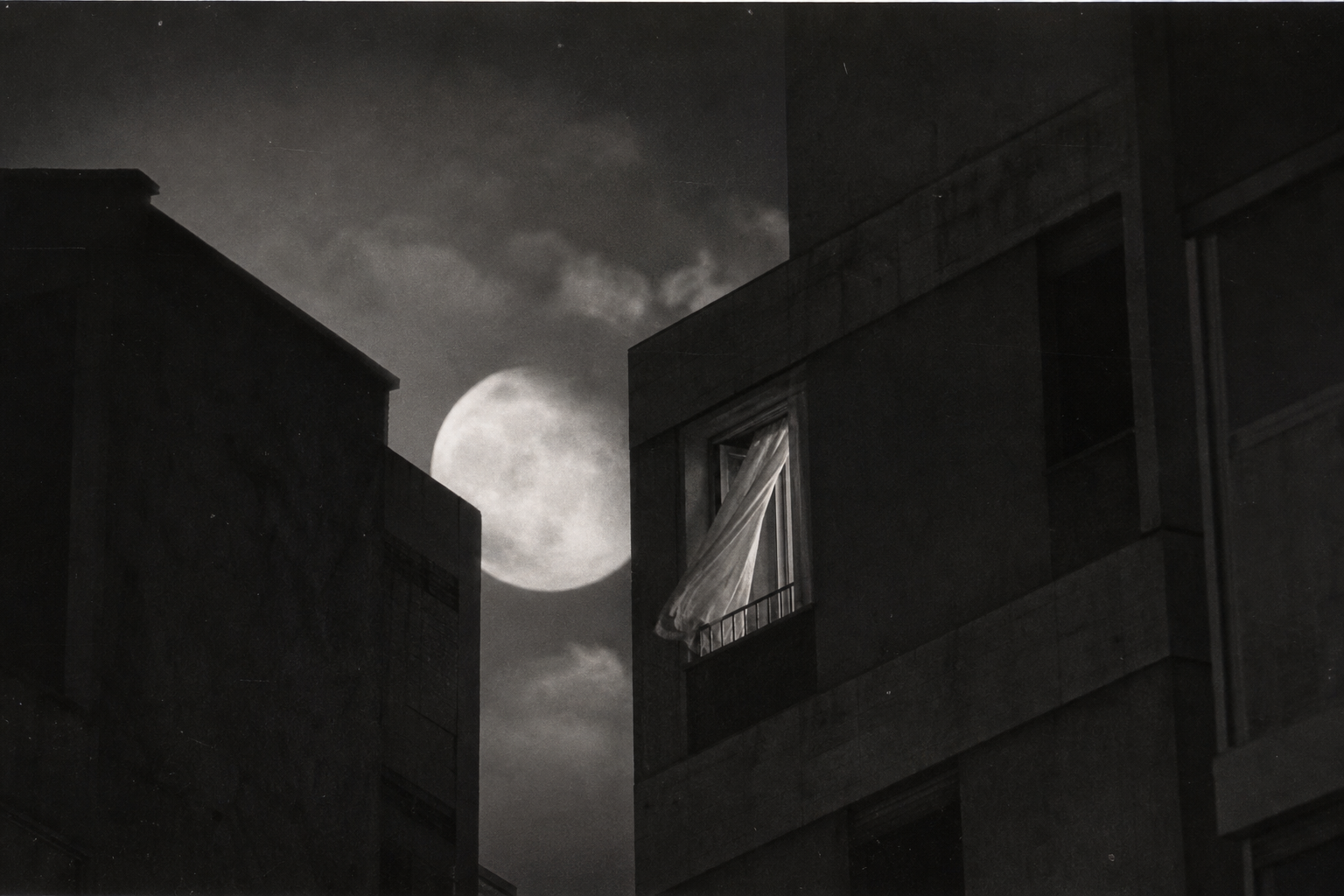 Monochrome urban night scene with moonlight, quiet buildings, and painterly grain