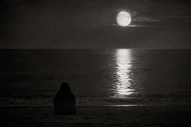 Dark moonlit sea beneath a partially eclipsed moon